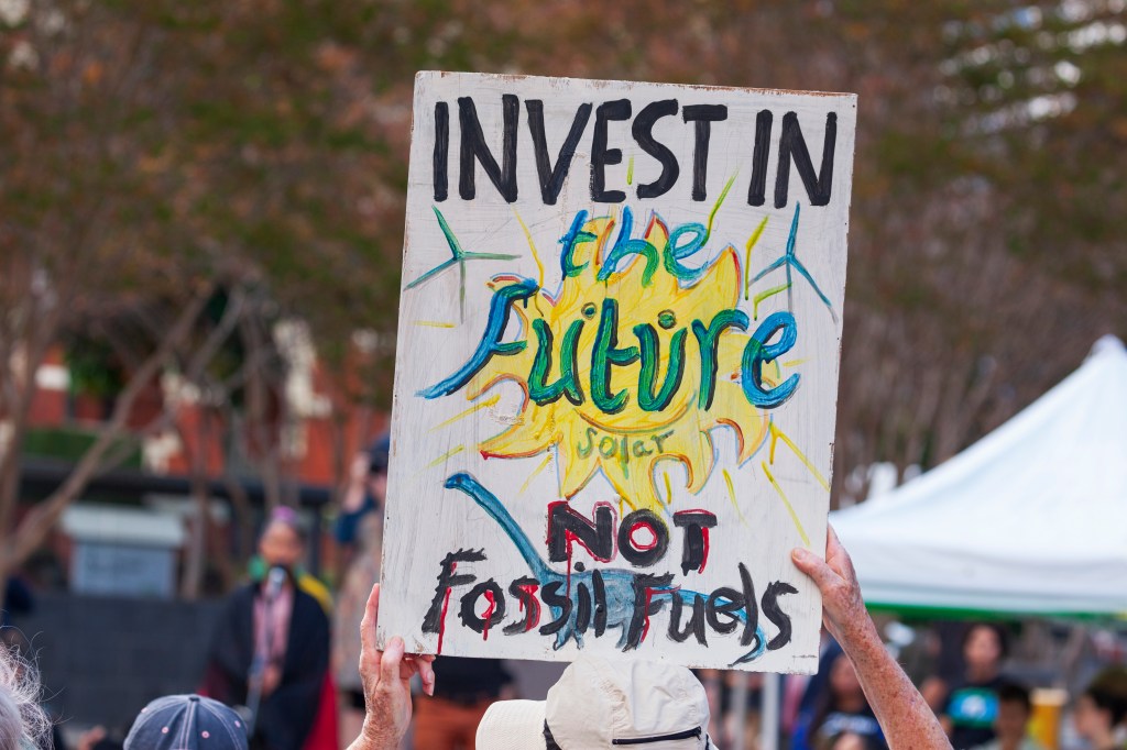 Sign reads invest in the future not fossil fuels at a protest rally in Brisbane.