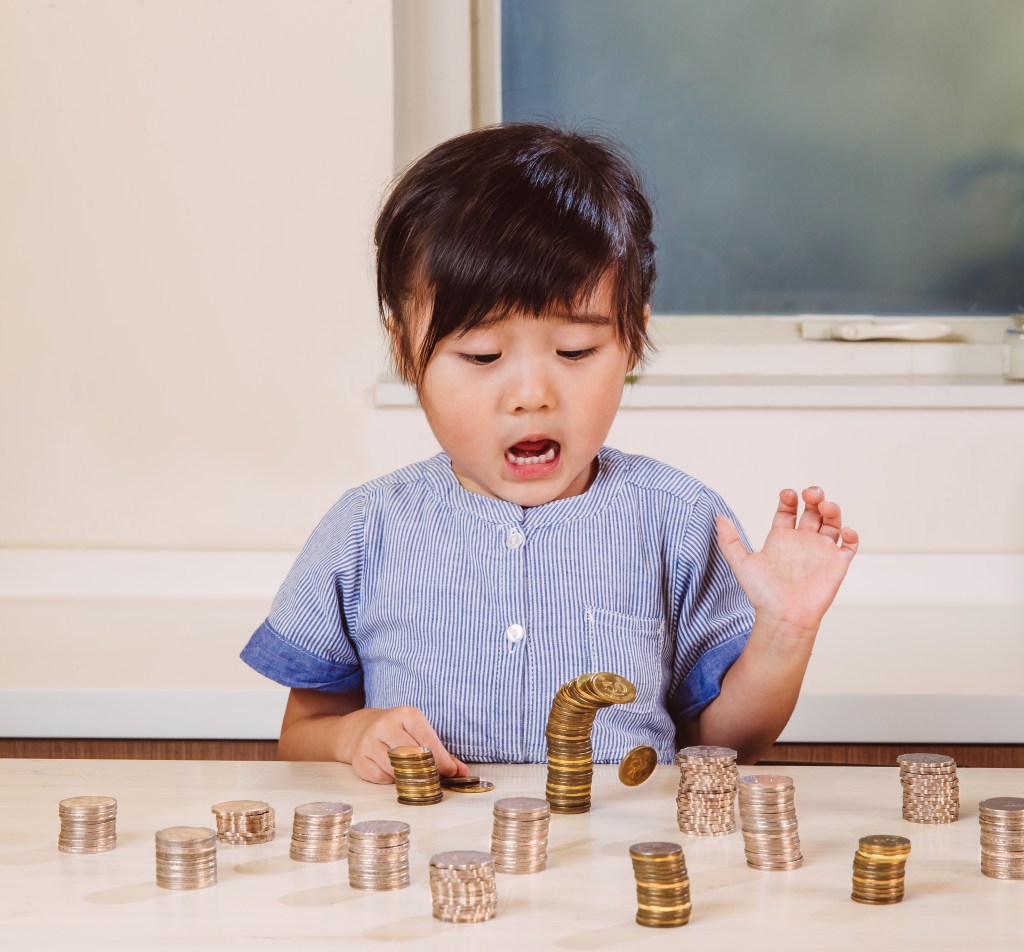 Child playing with coins. Changing your relationship with money will take a conscious and consistent effort. 
