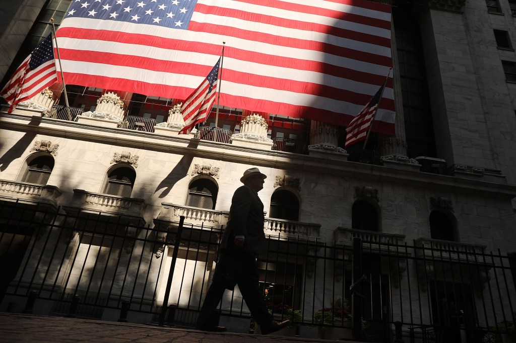 A man walks by the New York Stock Exchange (NYSE) | Photo by Spencer Platt/Getty Images