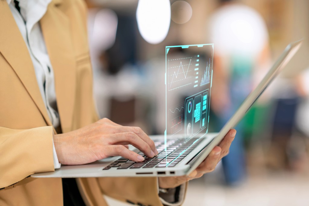 Close-up of businesswoman use computer while use digitization display for monitoring the data in business office.